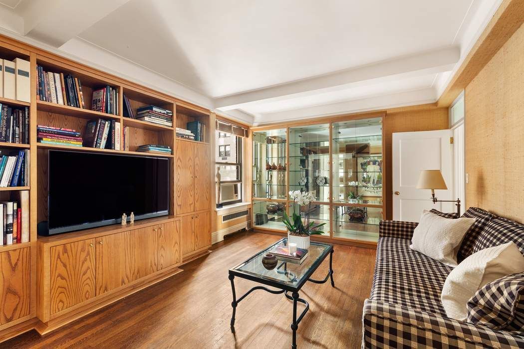 47 East 88th Street, Unit 8A Manhattan, NY 10128 - Photo 20 of 27 a living room with furniture a flat screen tv and a bookshelf