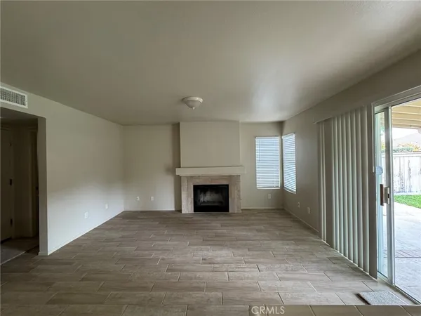 an empty room with windows fireplace and fans