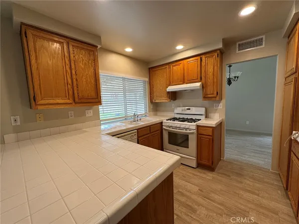 a kitchen with stainless steel appliances kitchen island wooden cabinets a stove a sink and a refrigerator