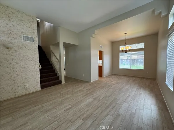an empty room with wooden floor staircase and windows