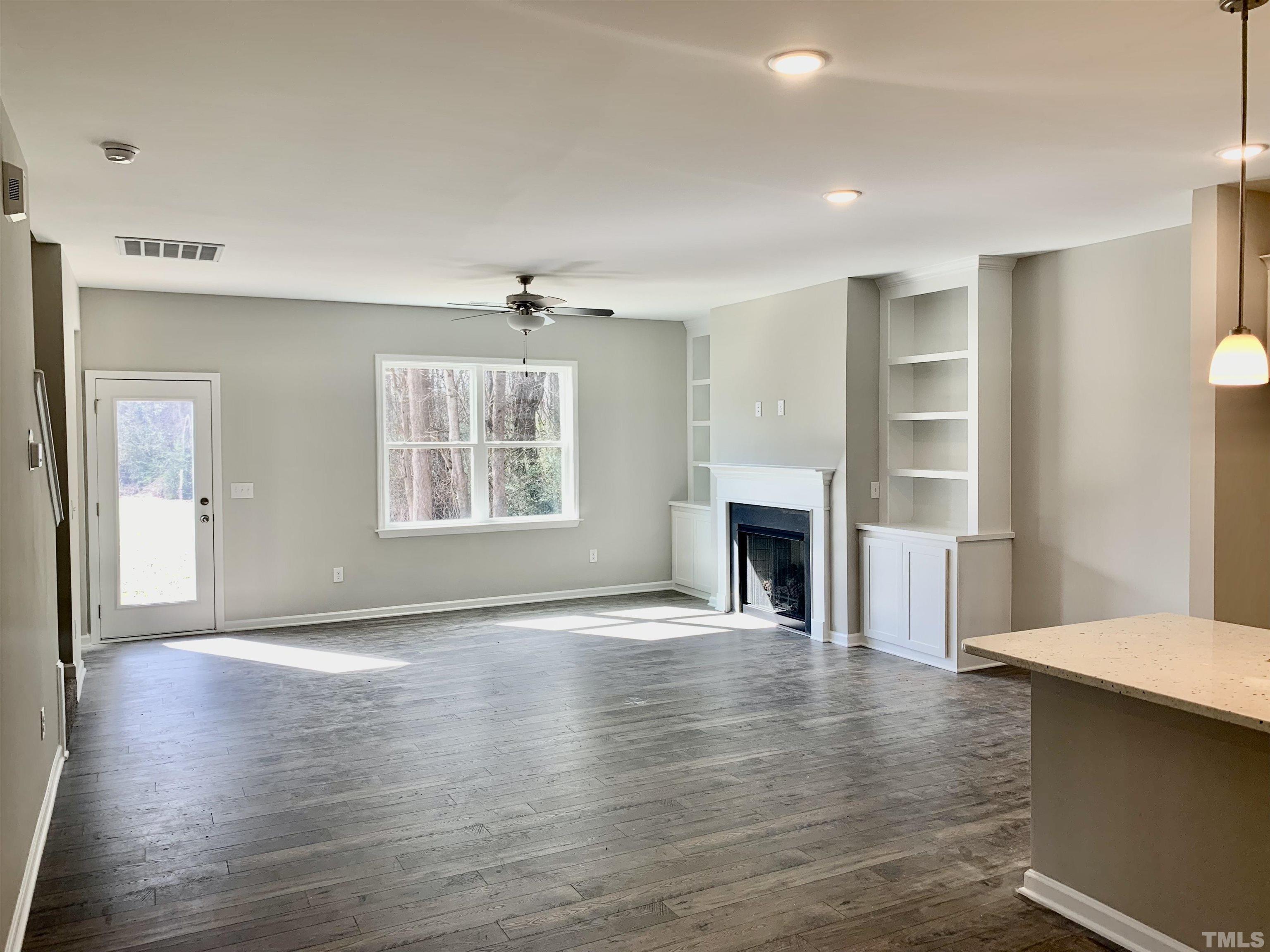 106 Two Daughters Streme Smithfield, NC 27577 - Photo 4 of 14 an empty room with wooden floor fireplace and windows