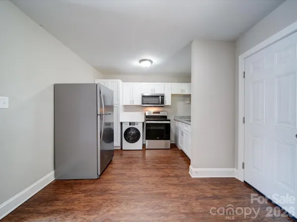 a kitchen with a refrigerator a stove top oven and white walls