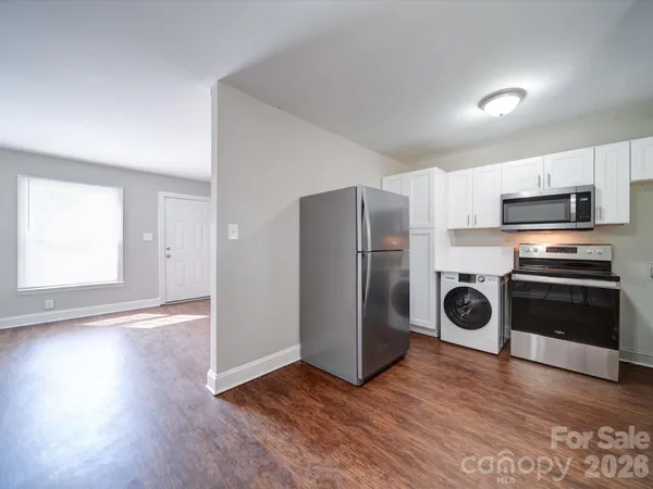 a kitchen with wooden floor sink and stainless steel appliances