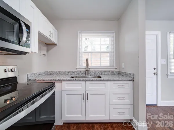 a kitchen with granite countertop a stove sink and microwave