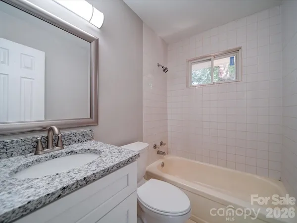 a bathroom with a granite countertop sink a toilet and bathtub