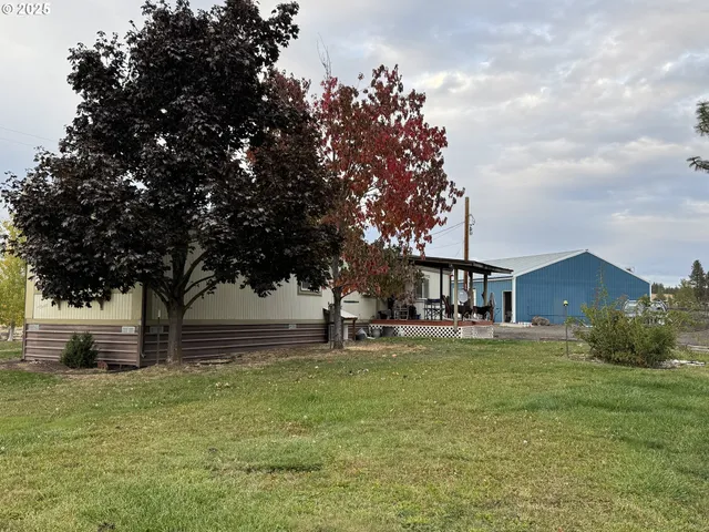 a white house with a big yard and large trees
