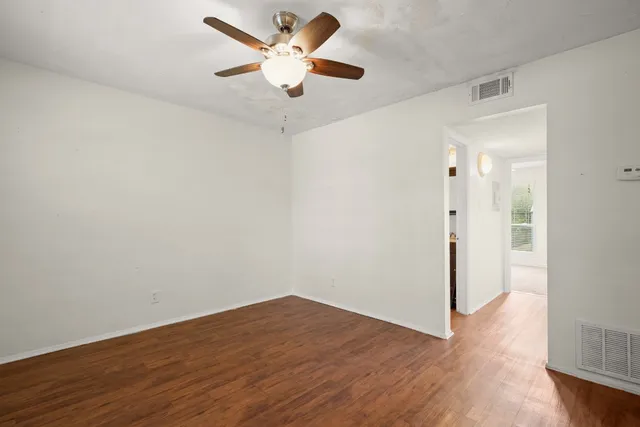 an empty room with wooden floor and a ceiling fan