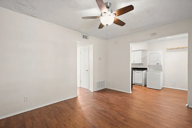 an empty room with wooden floor and ceiling fan