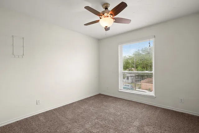 an empty room with a window and a fan
