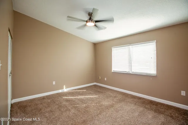 an empty room with a window and a fan