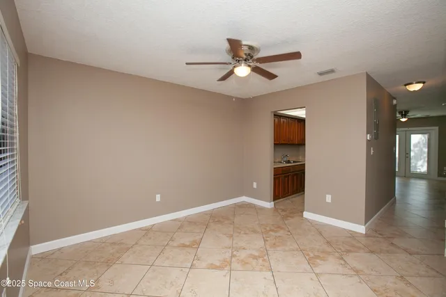 a view of an empty room with window and chandelier fan