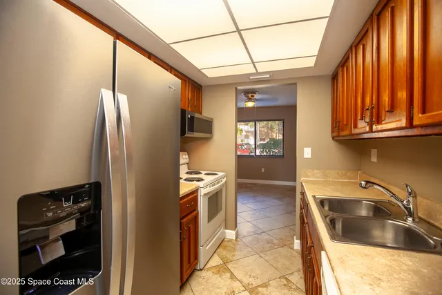 a kitchen with stainless steel appliances granite countertop a refrigerator a stove and a sink with wooden floor