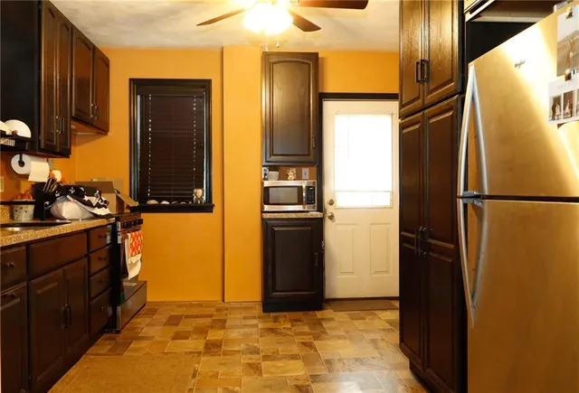 a view of a refrigerator in kitchen and an empty room