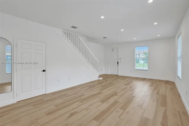 a view of empty room with wooden floor and fan