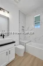 a bathroom with a granite countertop sink a toilet a mirror and bathtub