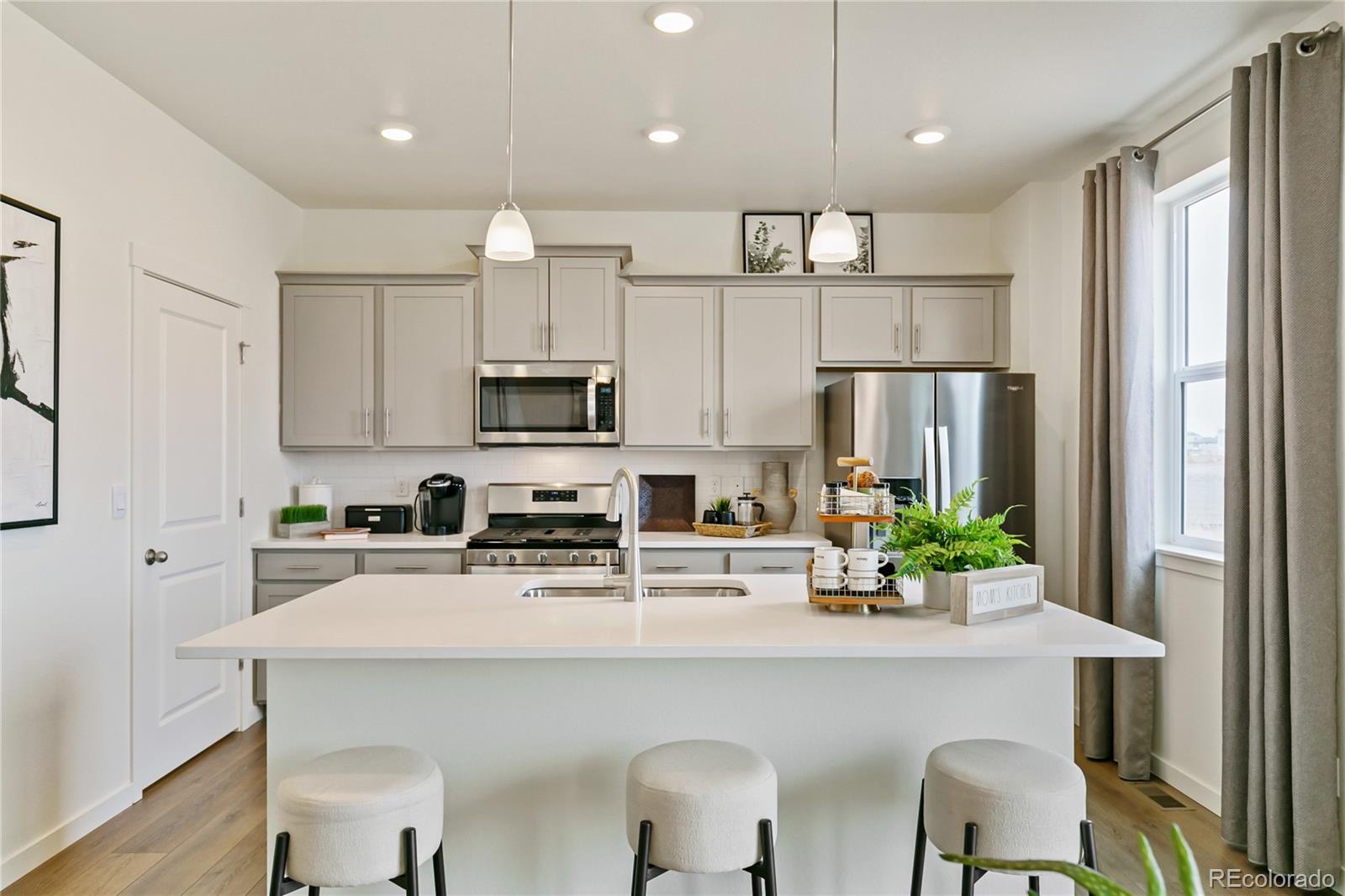 9935 Ceylon Court Commerce City, CO 80022 - Photo 9 of 44 a kitchen with white cabinets and refrigerator