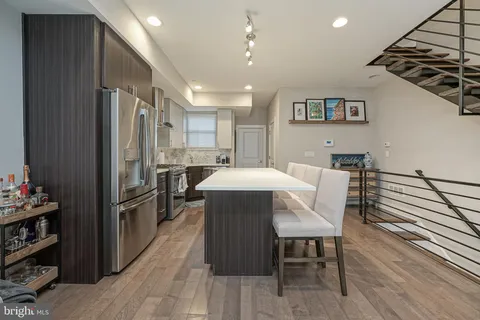 a kitchen with stainless steel appliances a table chairs refrigerator and cabinets