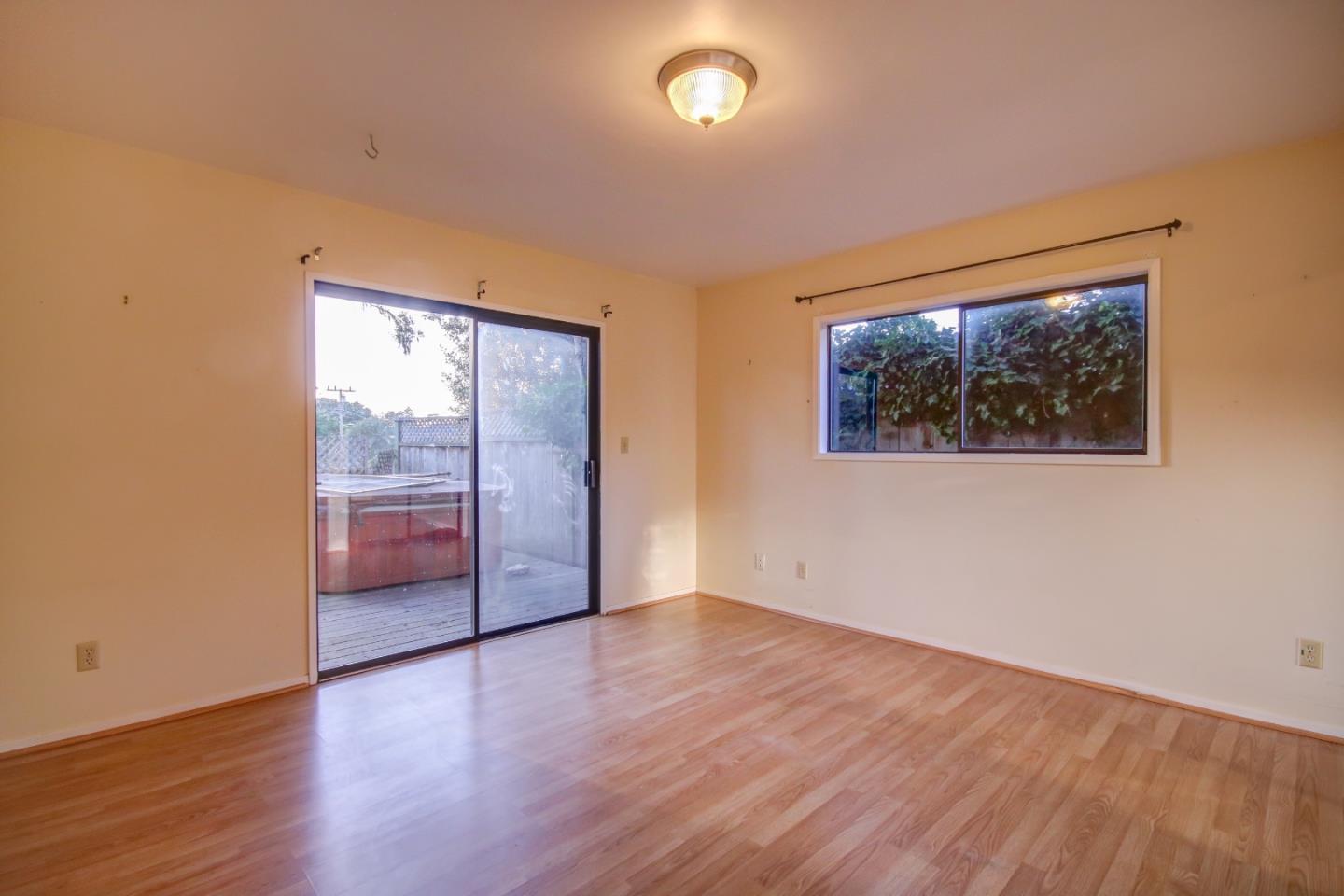 816 Gate Street Pacific Grove, CA 93950 - Photo 10 of 18 an empty room with wooden floor and windows