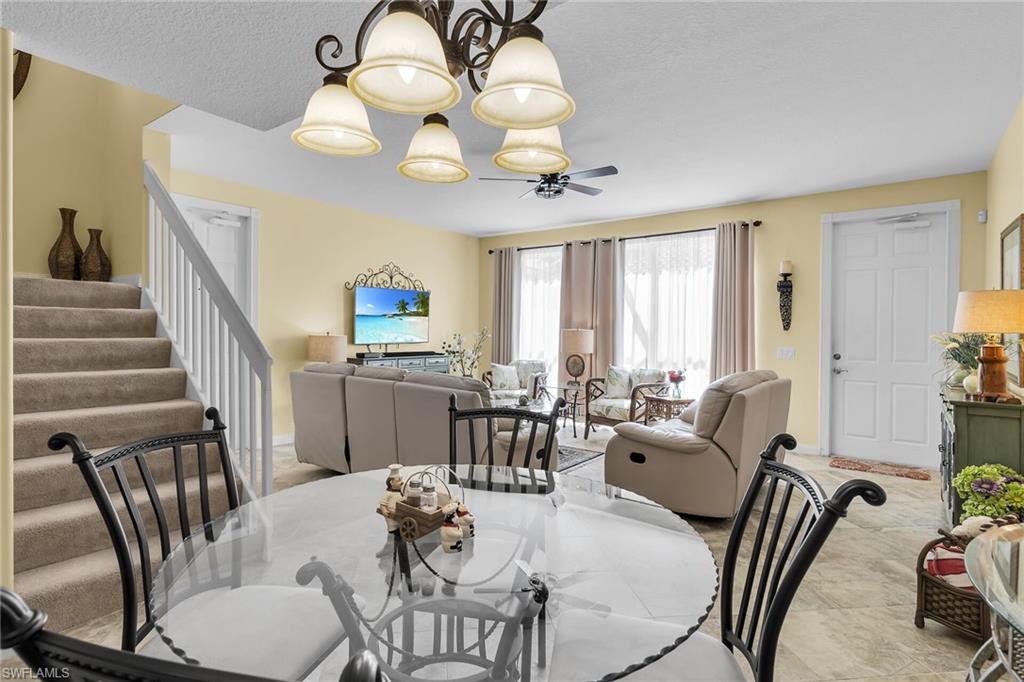 8044 Josefa Way Naples, FL 34114 - Photo 14 of 41 Dining space with stairway, a chandelier, and a textured ceiling