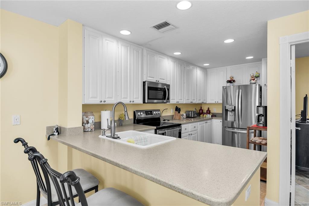 8044 Josefa Way Naples, FL 34114 - Photo 8 of 41 Kitchen with stainless steel appliances, a breakfast bar, a peninsula, white cabinets, and recessed lighting
