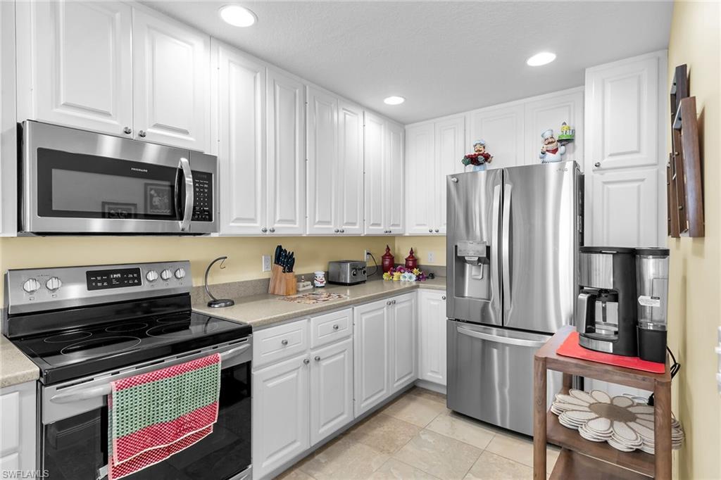 8044 Josefa Way Naples, FL 34114 - Photo 9 of 41 Kitchen featuring stainless steel appliances, white cabinetry, recessed lighting, and light tile patterned floors