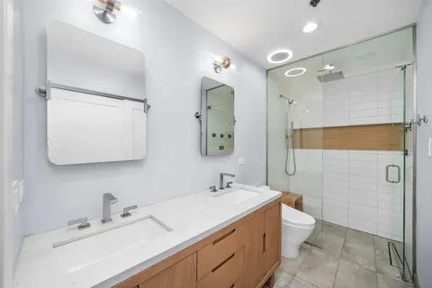 a bathroom with a double vanity sink mirror and shower