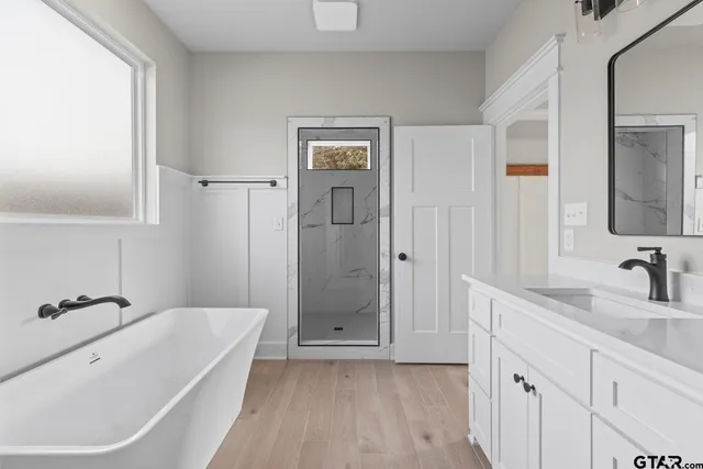 a bathroom with a tub a sink and mirror