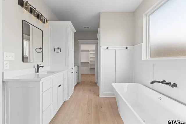 a bathroom with a tub sink a mirror and shower