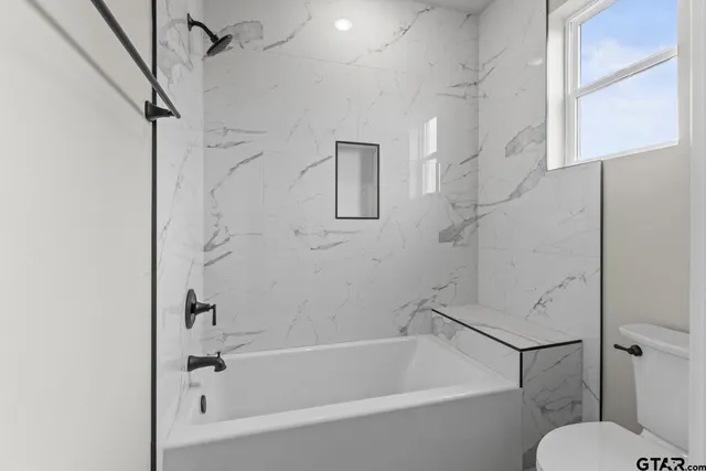 a white bath tub sitting next to a toilet