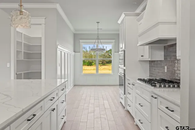a kitchen with granite countertop a stove a sink and dishwasher with white cabinets