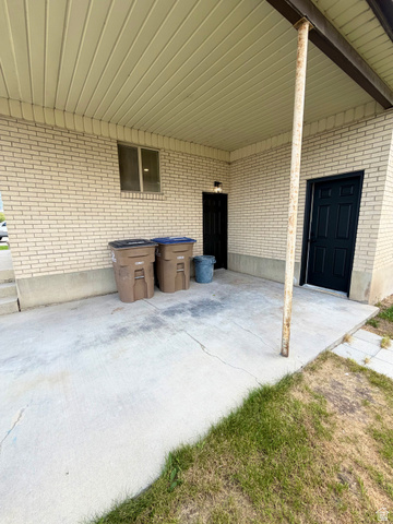 450 13800 South, Unit 2 Draper, UT 84020 - Photo 21 of 21 Covered concrete patio with light brick exterior, featuring two black doors and an exterior light fixture