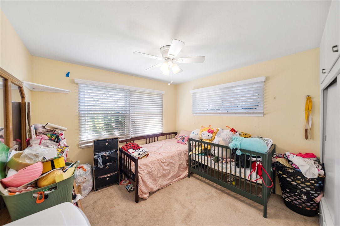 5433 Rochester Street Riverside, CA 92504 - Photo 14 of 29 Bedroom with two windows, ceiling fan, carpeting, and built-in storage along one wall.