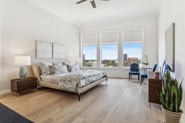 a bedroom with a bed a large window and a potted plant