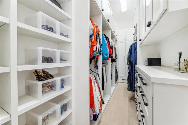 a view of walk in closet with clothes shoes and a cabinets