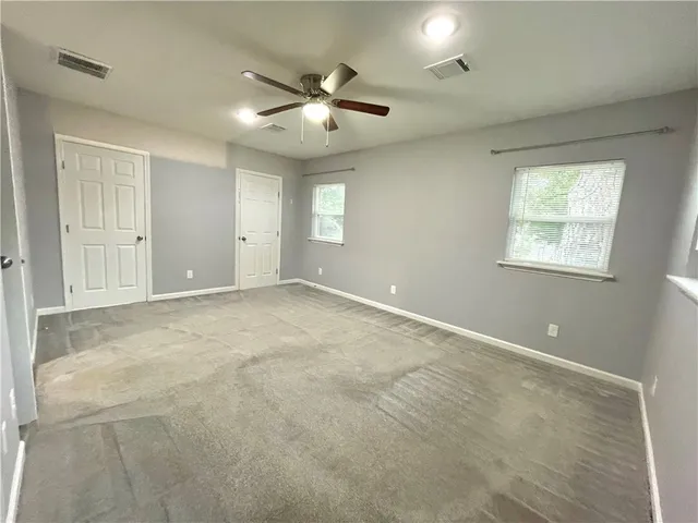 an empty room with windows and fan