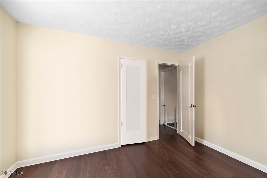 187 Everhard Road Southwest North Canton, OH 44720 - Photo 10 of 19 Spare room featuring dark wood-style flooring and a textured ceiling