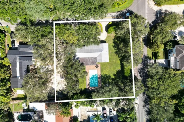 an aerial view of residential houses with outdoor space and trees