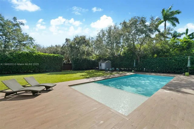 a view of backyard with a bench and trees