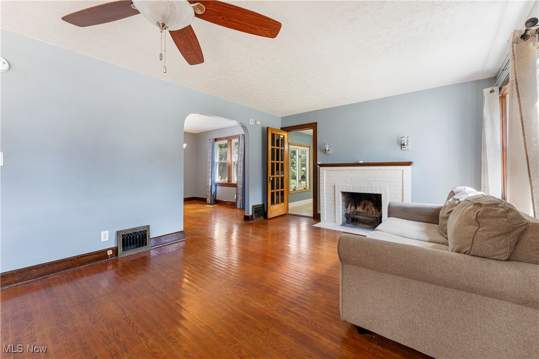 1623 Spangler Road Northeast Canton, OH 44714 - Photo 5 of 28 Living area with dark wood finished floors, arched walkways, a brick fireplace, ceiling fan, and a textured ceiling