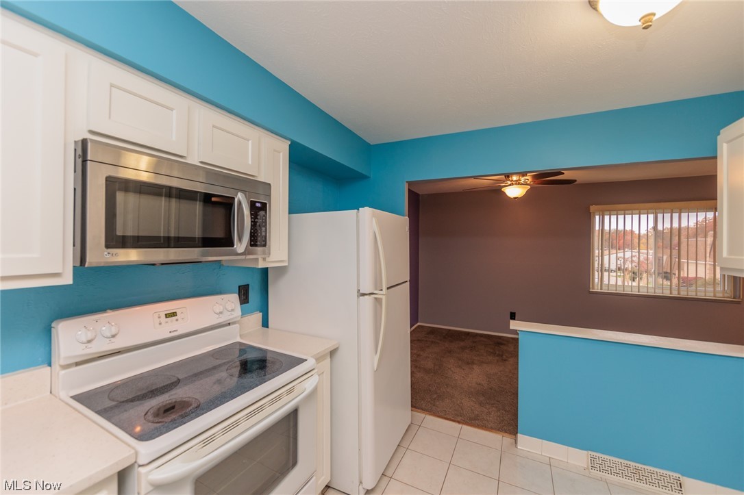 6472 State Road, Unit J19 Parma, OH 44134 - Photo 15 of 33 Kitchen with white appliances, ceiling fan, white cabinetry, and light carpet