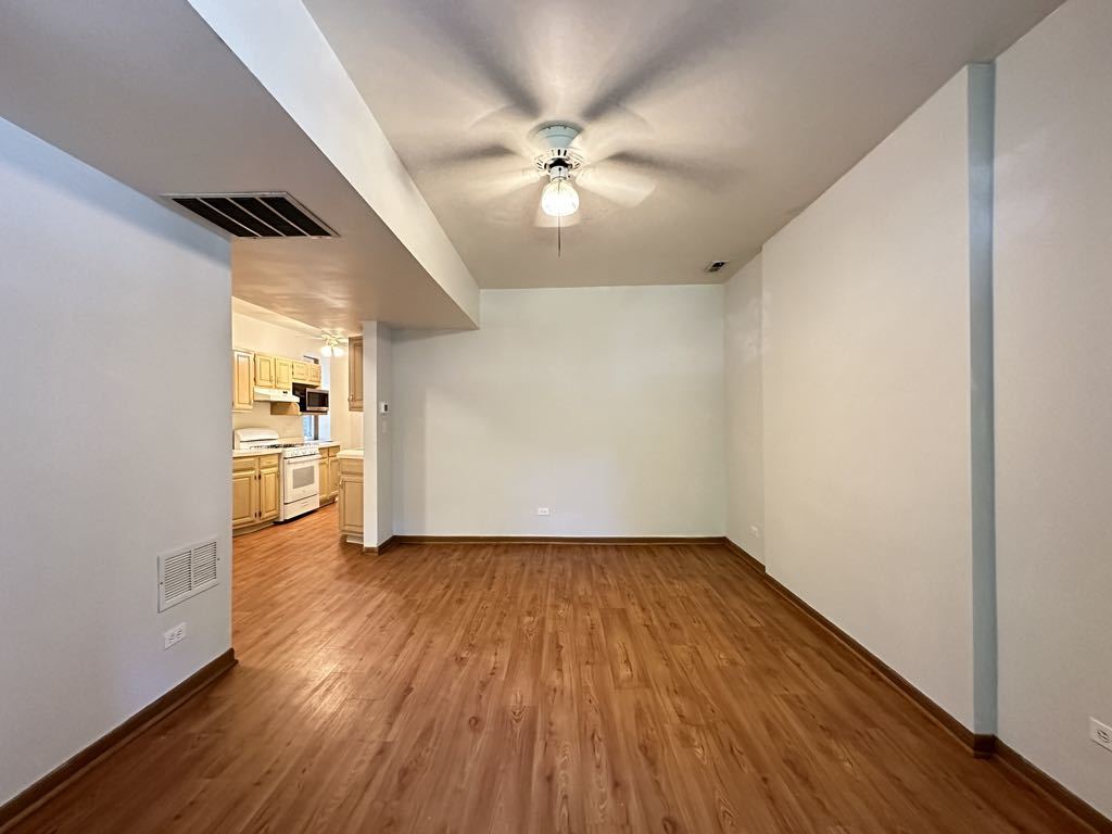 3832 North Fremont Street, Unit G Chicago, IL 60613 - Photo 14 of 20 an empty room with wooden floor fan and windows