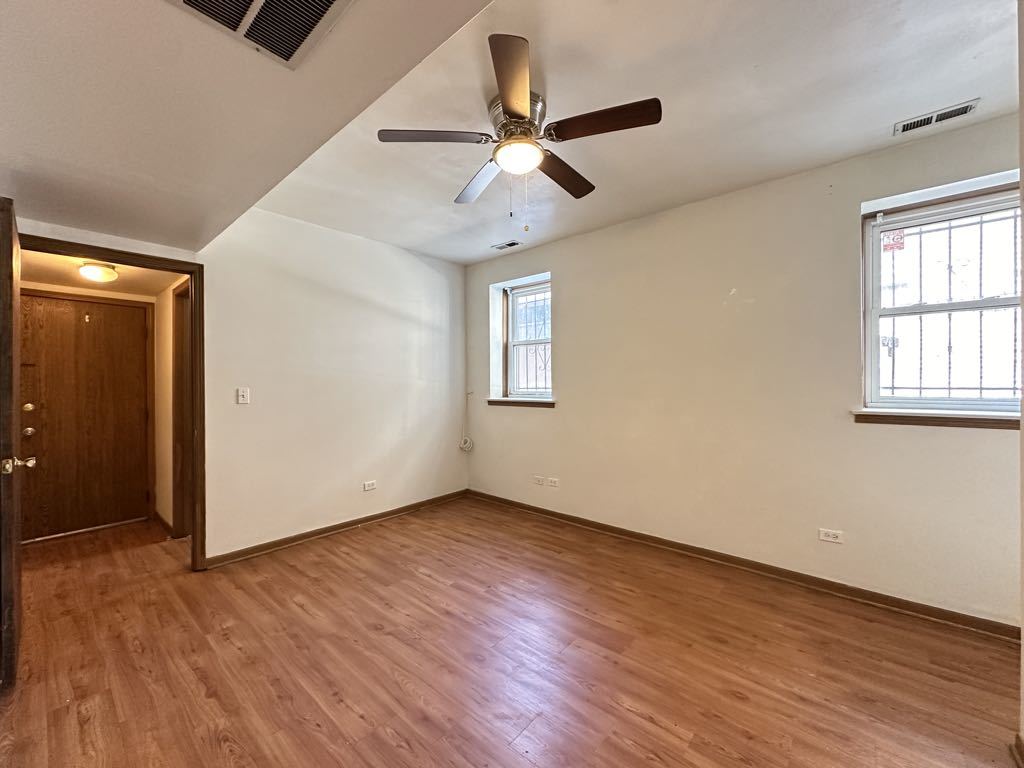 3832 North Fremont Street, Unit G Chicago, IL 60613 - Photo 18 of 20 an empty room with wooden floor chandelier fan and windows