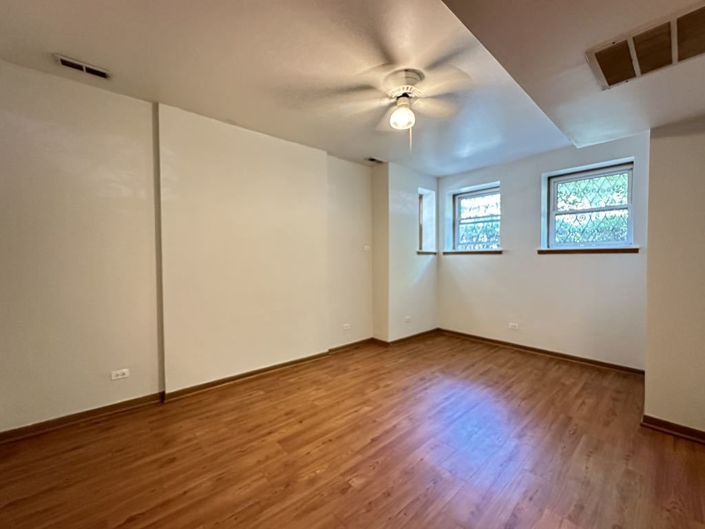 3832 North Fremont Street, Unit G Chicago, IL 60613 - Photo 10 of 20 an empty room with wooden floor chandelier fan and windows