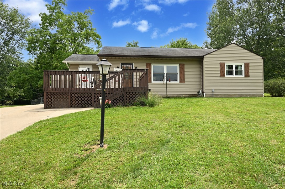 View of front of home with a deck and a front yard