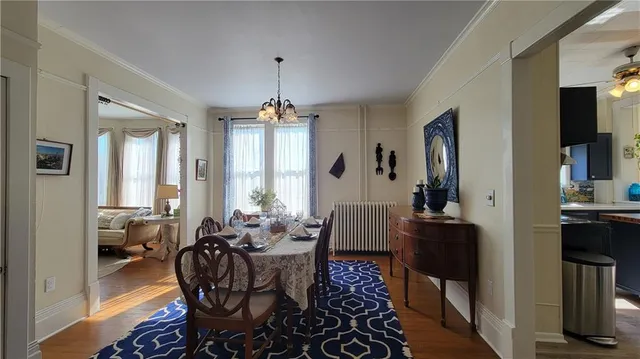a view of a dining room and livingroom with furniture wooden floor a chandelier and a rug