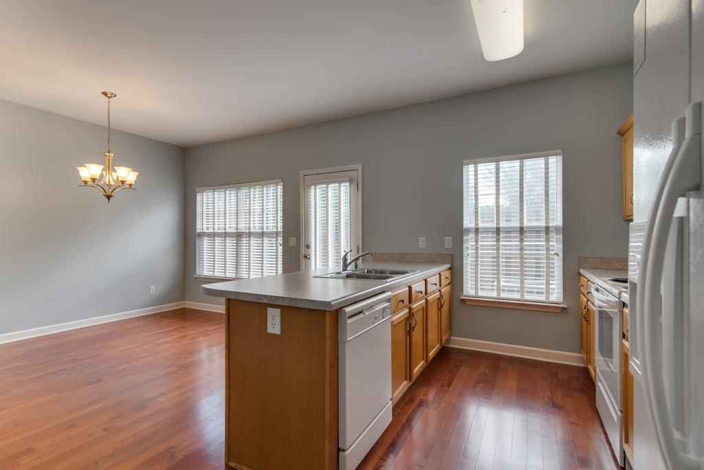 553 Rosedale Avenue, Unit 127 Nashville, TN 37211 - Photo 9 of 27 an open kitchen with granite countertop a stove a sink a refrigerator wooden floor and a fireplace