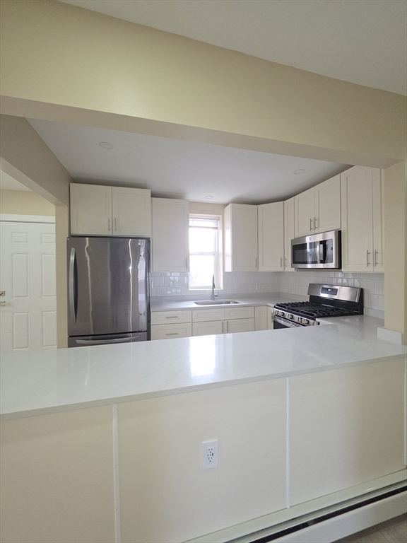 475 Purchase Street, Unit 3 New Bedford, MA 02740 - Photo 12 of 20 a large white kitchen with stainless steel appliances a large window