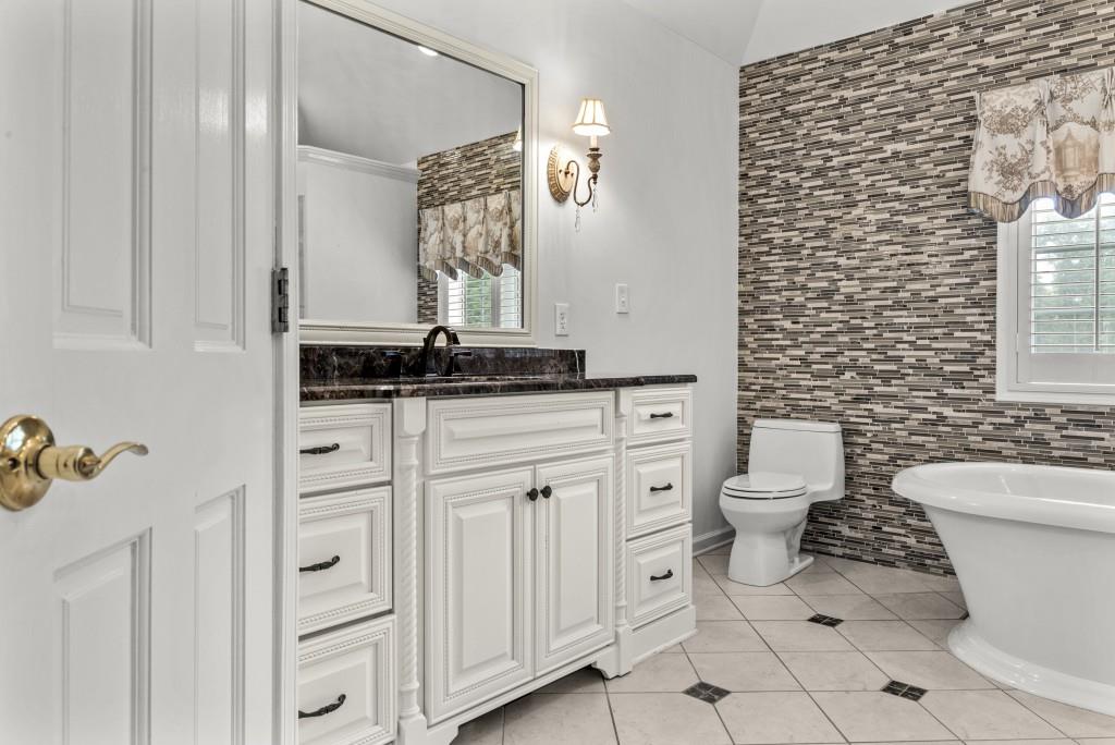 300 Potts Lane Covington, GA 30016 - Photo 48 of 76 a bathroom with a granite countertop toilet a sink a mirror and shower curtain