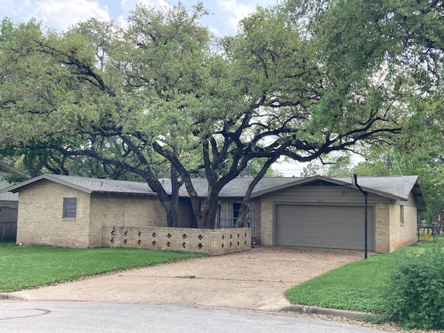 a front view of a house with a garden and trees