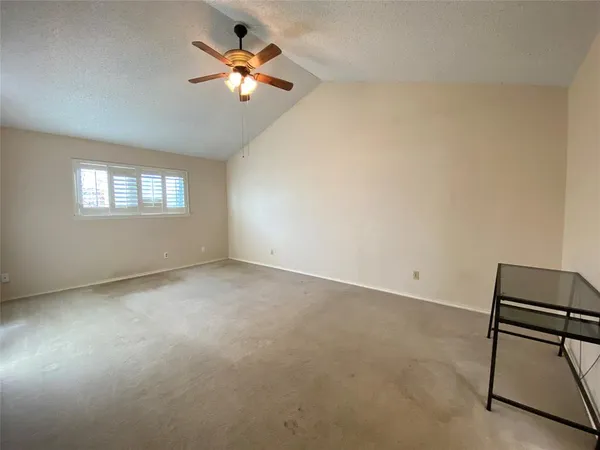 an empty room with windows and fan